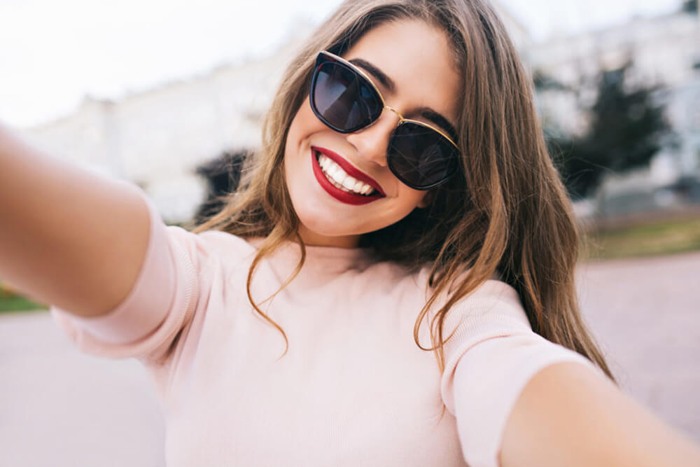 Girl-with-sunglasses-taking-a-selfie-in-camera-phone