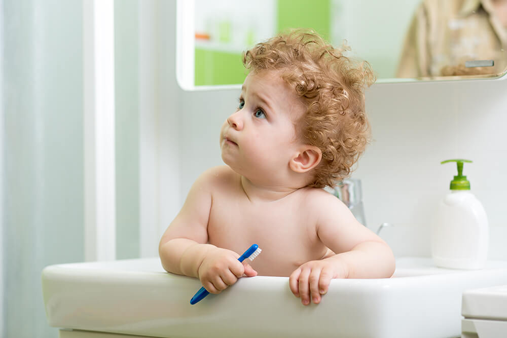Little child with toothbrush sitting in the sink