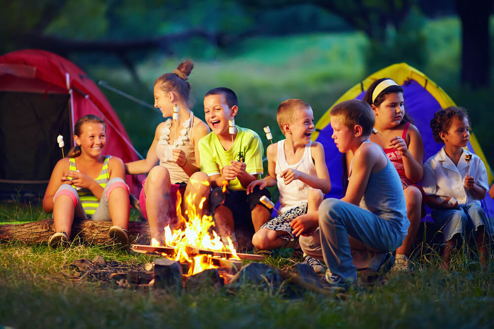 Children sitting around a campfire eating a s’mores
