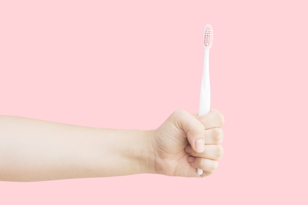 Woman’s hand holding white toothbrush