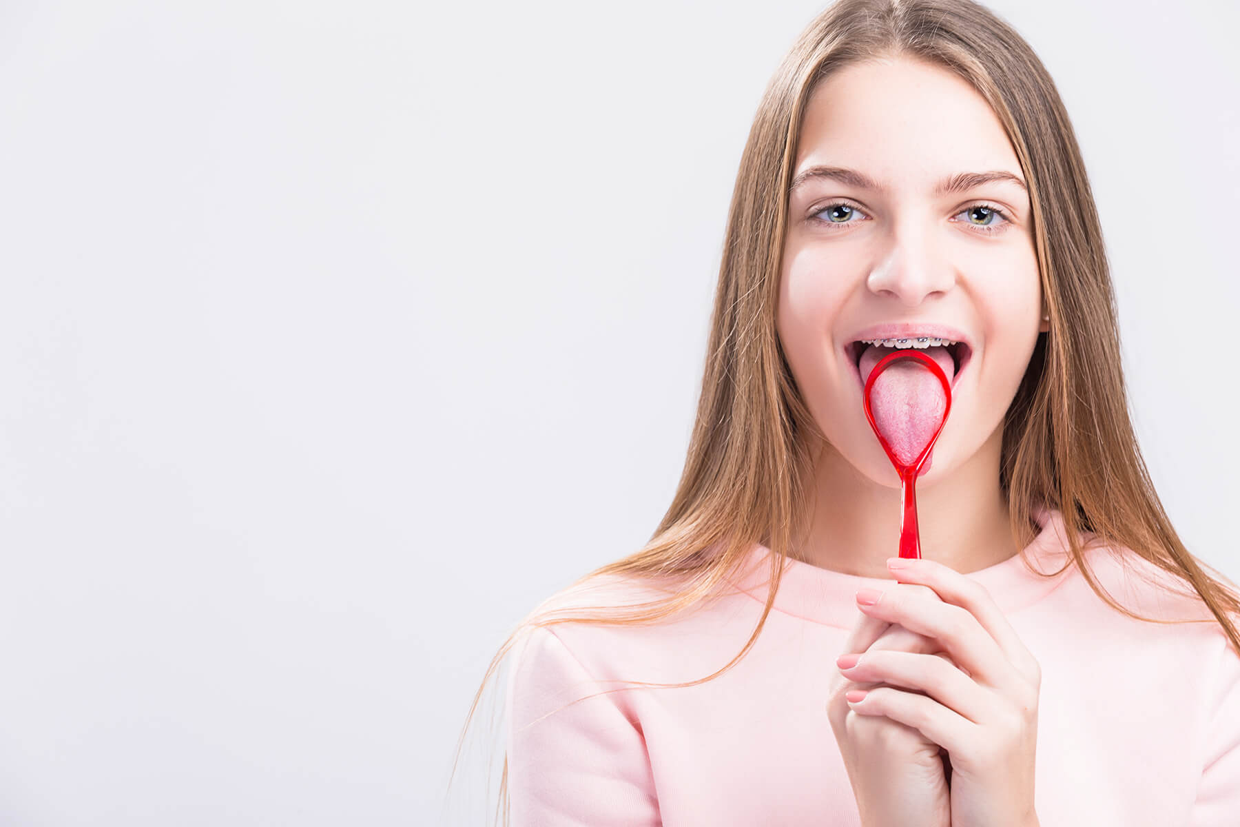 Woman with braces cleaning her tongue