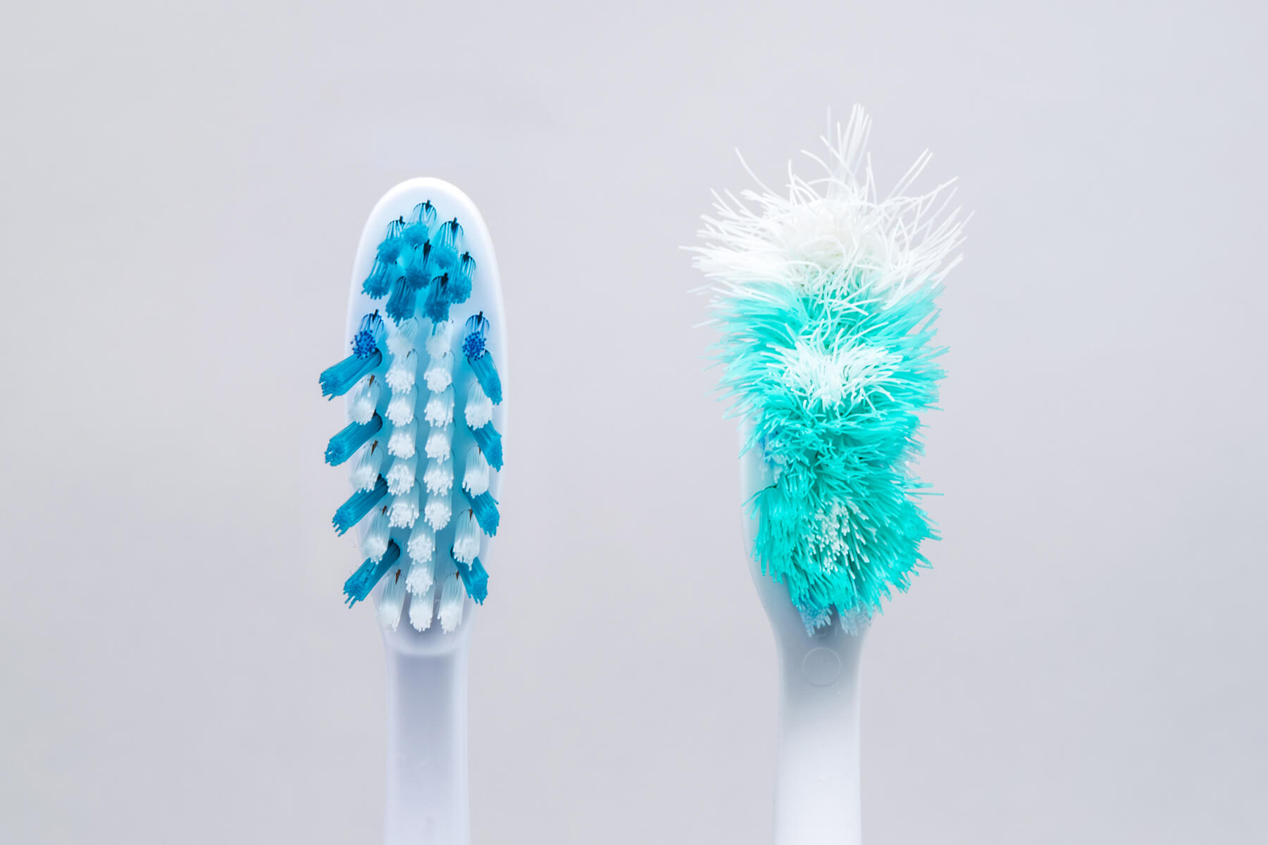 Brand new toothbrush next to old frayed toothbrush