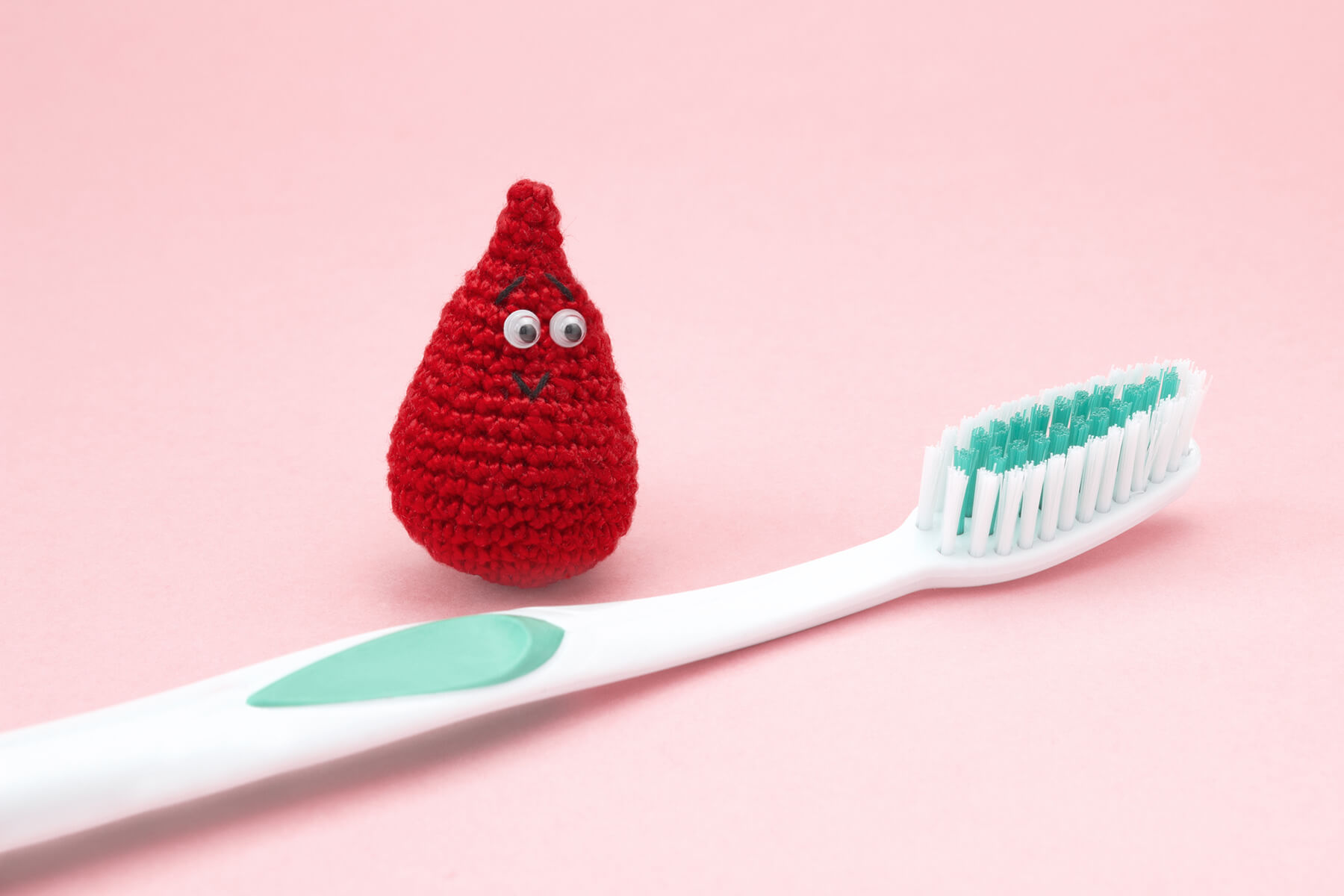 Blood droplet mascot standing next to a toothbrush