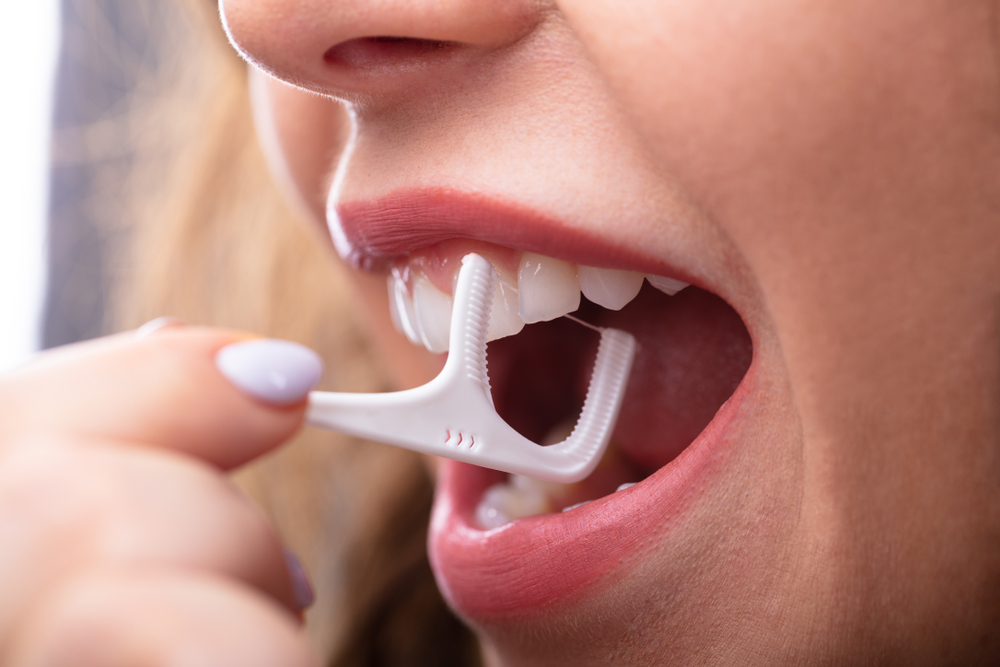 Closeup of young woman using a floss pick for dental care
