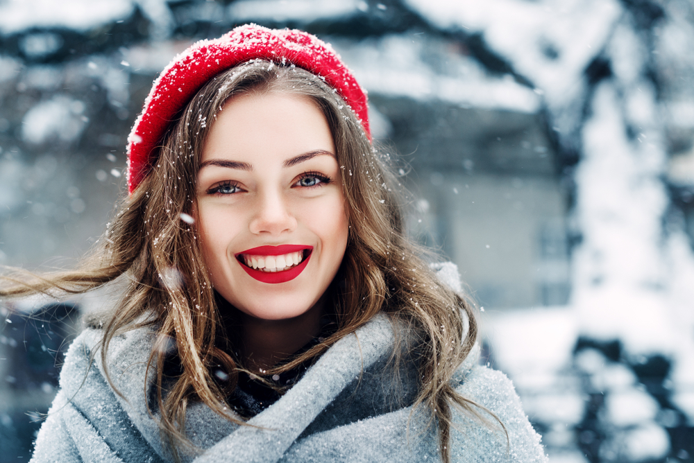 Beautiful young woman smiling as snow falls around her