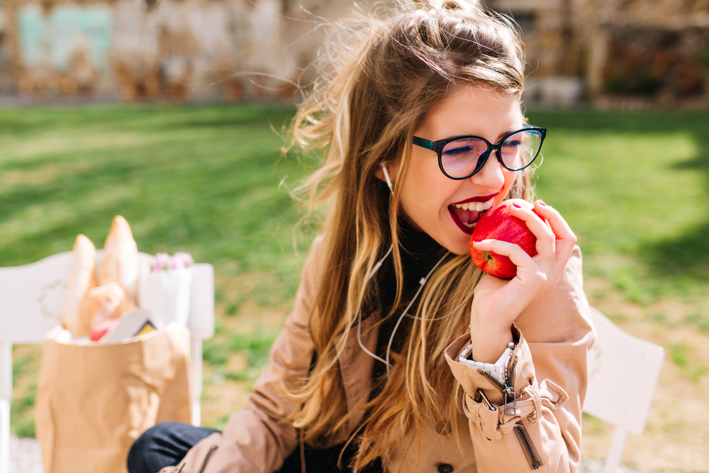 Young woman eating an apple on a picnic