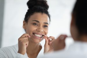 Woman Flossing While Looking in the Mirror